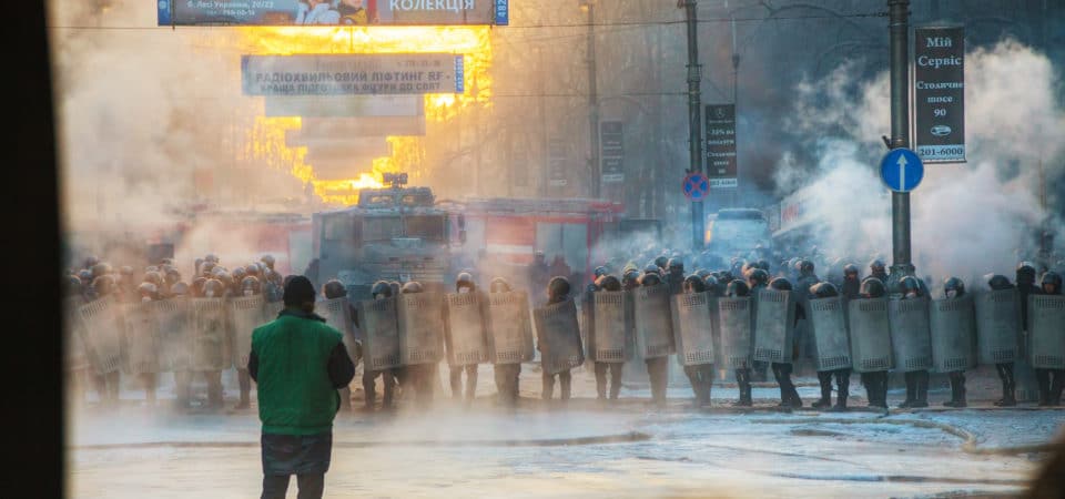 KIEV UKRAINE - JANUARY 24: A row of the riot police with a priest at Hrushevskogo street on January 24 2014 in Kiev Ukraine. The anti-governmental protests were provoked when the Ukrainian president denied to sign an agreement with the EU.