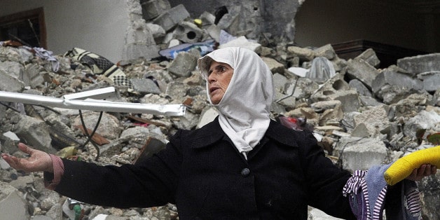 FILE - In this Wednesday, Feb. 6, 2013 file photo, a Syrian woman stands amid the ruins of her house which was destroyed in an airstrike by government warplanes a few days earlier, killing 11 members of her family, in the neighborhood of Ansari, Aleppo, Syria. President Bashar Assad has exploited his greatest advantage on the battlefield _ his air power _ to push back rebel advances and prevent the opposition from setting up a rival government in its northern stronghold. Along the way, fighter jets and helicopters bombed bakeries, makeshift hospitals and residential areas, according to a new report by a U.S.-based rights group released Thursday, April 11, 2013 accusing the regime of committing war crimes with indiscriminate airstrikes that have killed more than 4000 since summer. (AP Photo/Abdullah al-Yassin, File)